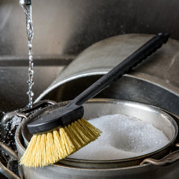 A Carlisle yellow Sparta utility brush scrubbing a pot.