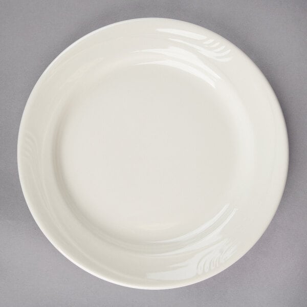 A Oneida Espree cream white china plate on a gray surface.