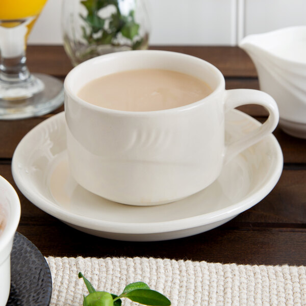 A Oneida Odyssey saucer holding a cup of coffee on a table.
