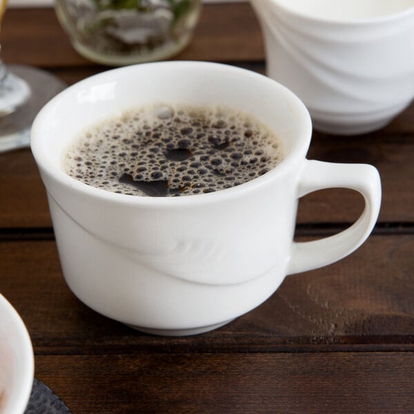 A close up of a white Oneida Espree Lotus cup with brown liquid in it.