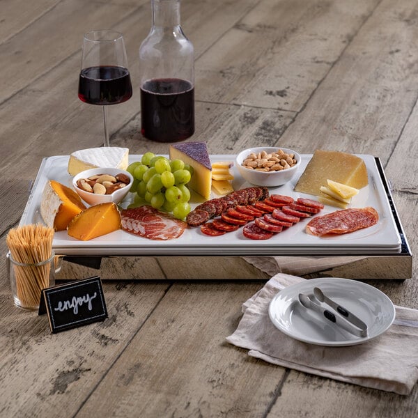 A Frilich stainless steel rectangular cooling plate with food on it displayed on a table.