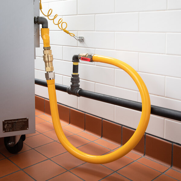 A yellow Regency gas connector hose kit connected to a metal pipe.