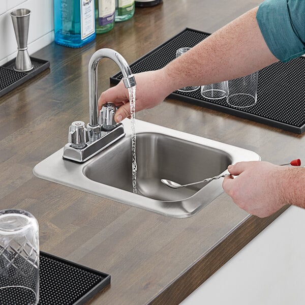 A person washing their hands in a Regency stainless steel drop-in sink.