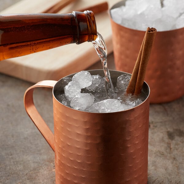 Person pouring ginger beer into a copper mug