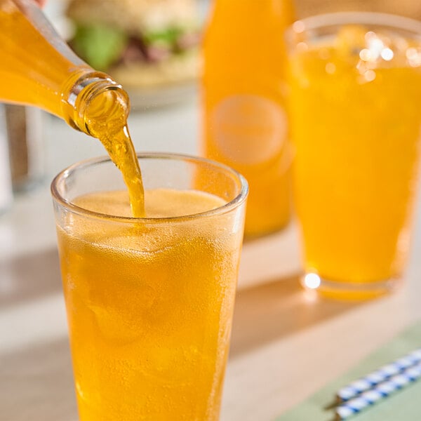 A person pouring Boylan Bottling Co. orange soda into a glass.