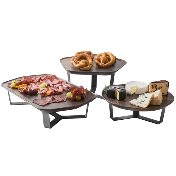 A Rosseto walnut polygon tray with a variety of food including meat, fruit, and cheese on a hotel buffet table.