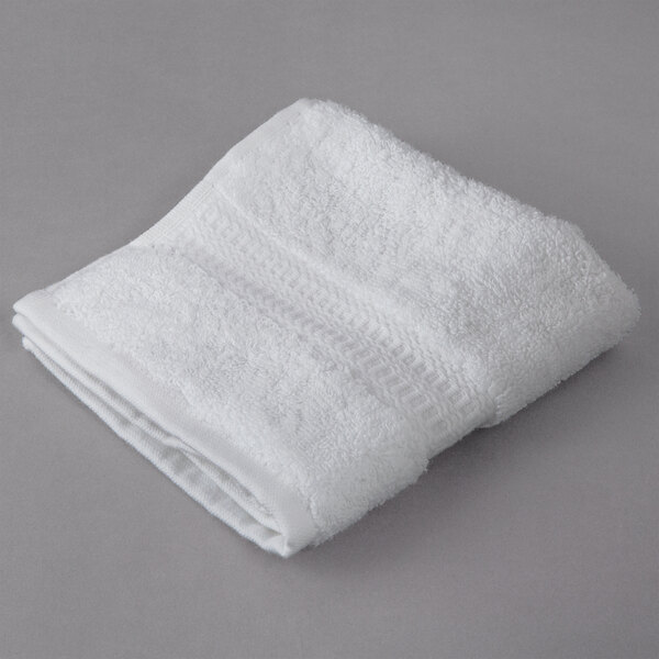 A folded white Oxford Reserve wash cloth on a gray surface.