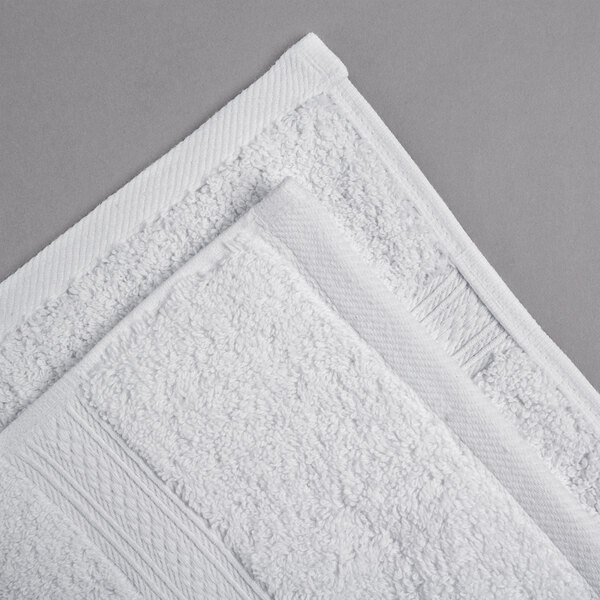 An Oxford Vicenza Bianco white hand towel with a dobby border on a gray surface.