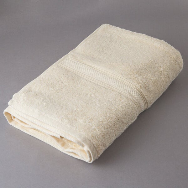 An Oxford Vicenza Avorio white bath towel on a gray surface.