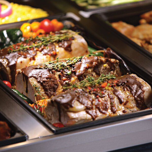 An Alto-Shaam heated display case on a counter filled with trays of food.