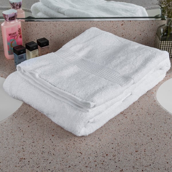 A stack of Oxford Reserve white bath towels on a white surface.