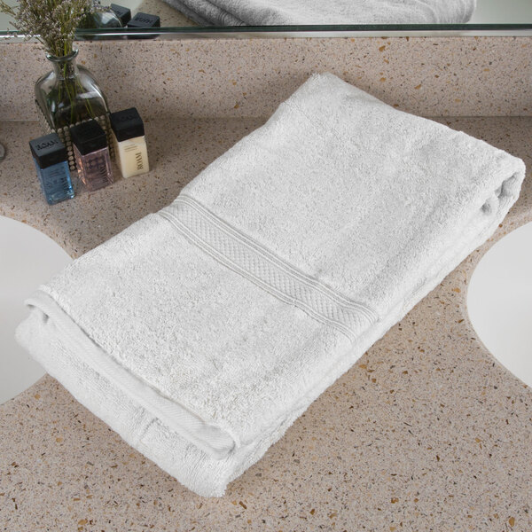 An Oxford Vicenza Bianco white bath towel with a dobby border on a white counter.