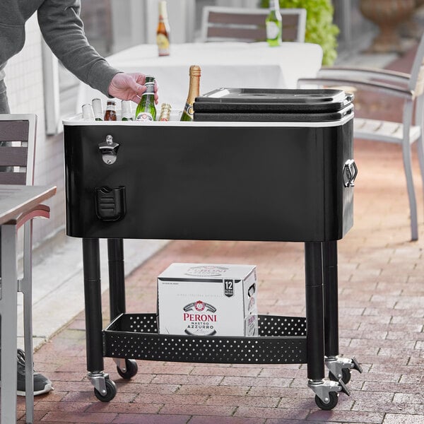 A man using a Choice black beverage cooler cart to chill bottles of beer outdoors.