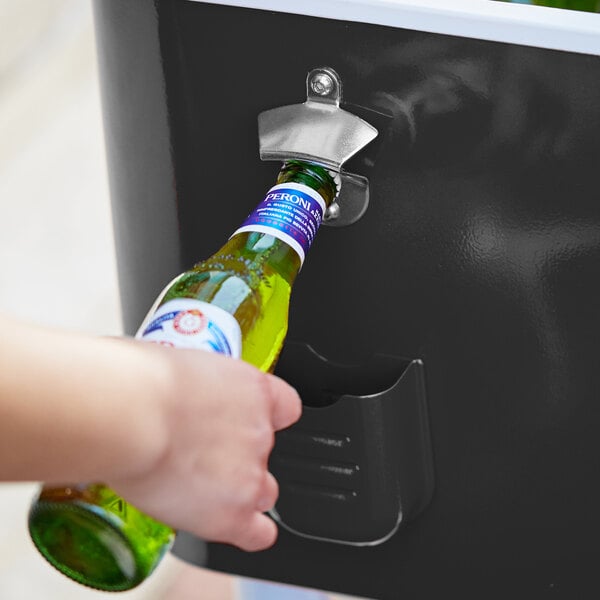 A hand using the Choice Black Beverage Cooler Cart to open a green bottle of beer.