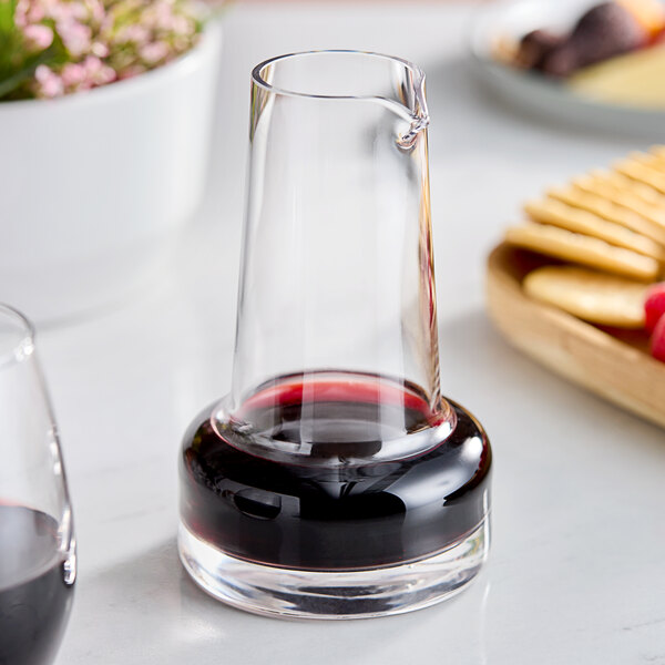 A glass of red wine with an American Metalcraft glass carafe on a table.