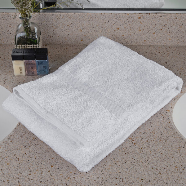 An Oxford Regale white bath towel on a white counter top.