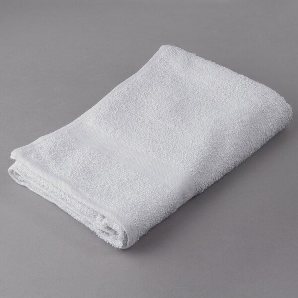 An Oxford Gold white bath towel with a cam border on a gray surface.