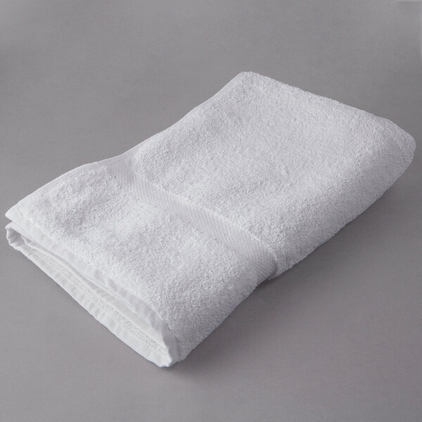 A folded white Oxford Regale bath towel with a dobby border on a gray surface.