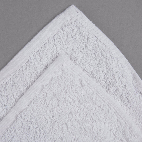 A white Oxford Regale bath towel with a dobby border on a gray surface.