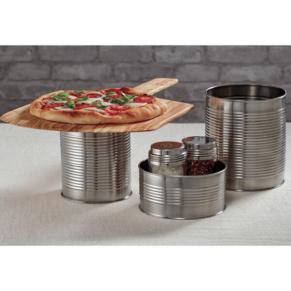 A pizza on a table with a soup can used as a riser.
