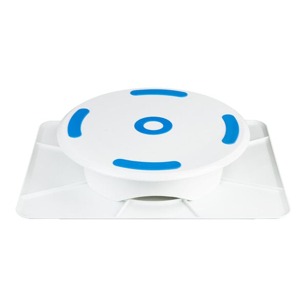A white plastic revolving cake stand with blue non-slip grips on a rectangular base.