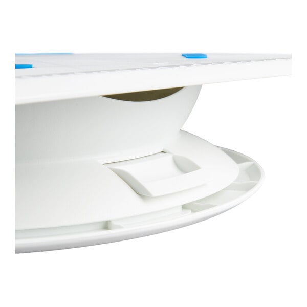 A close-up view of a white plastic revolving cake stand or turntable with a smooth surface and blue accents.
