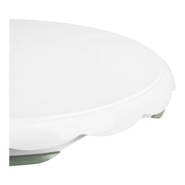 A close-up view of a white, round plastic surface with a slightly raised edge, likely part of a turntable or stand.
