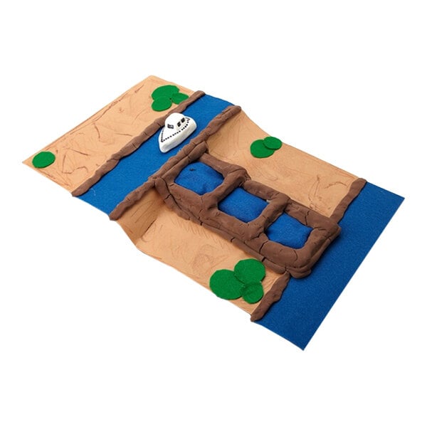 A handmade model of a bridge over a river with green patches and a small white boat, crafted from modeling clay in various colors.
