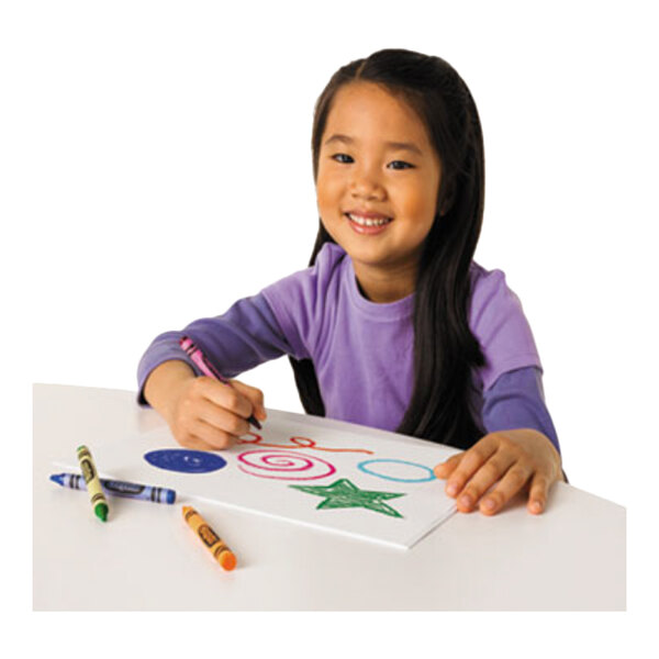 A young girl is drawing colorful shapes on paper with crayons at a white table, with several crayons scattered nearby.