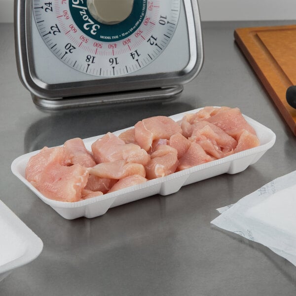 A white foam CKF meat tray holding raw chicken on a counter.