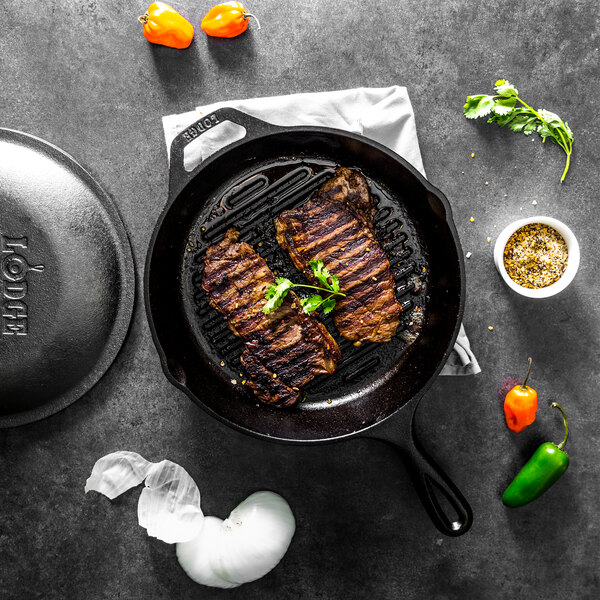 A Lodge cast iron grill pan with steak cooking in it.