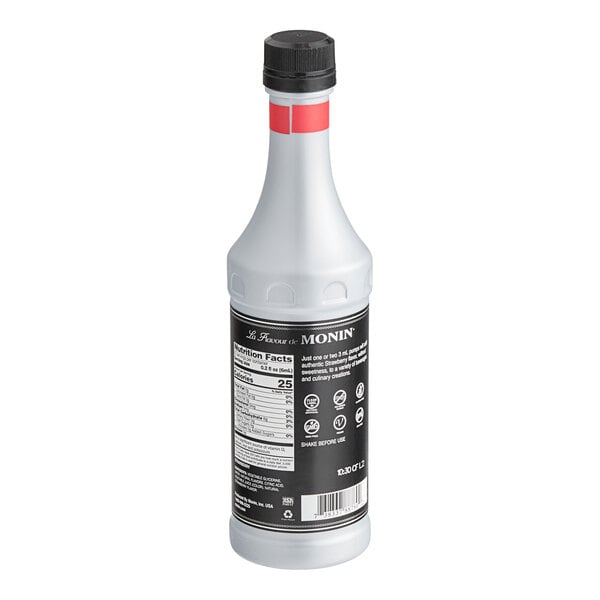 A white Monin bottle with a black label filled with liquid.