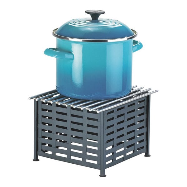 A black iron chafer alternative with a metal grate top, shown holding a blue pot with a lid.