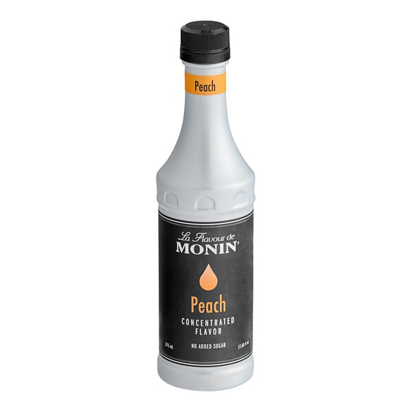 A white Monin bottle of peach concentrated flavor with a black label.