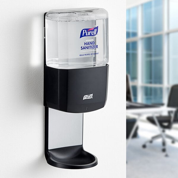 A graphite Purell automatic hand sanitizer dispenser on a wall.