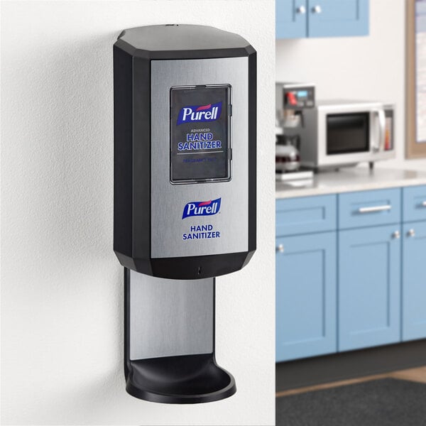 A black Purell automatic hand sanitizer dispenser on a wall.