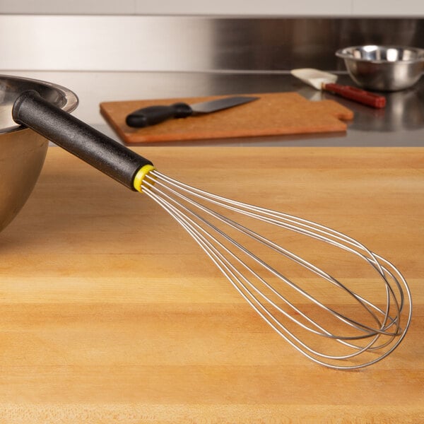 A Matfer Bourgeat stainless steel whisk with an Exoglass handle on a wooden surface.