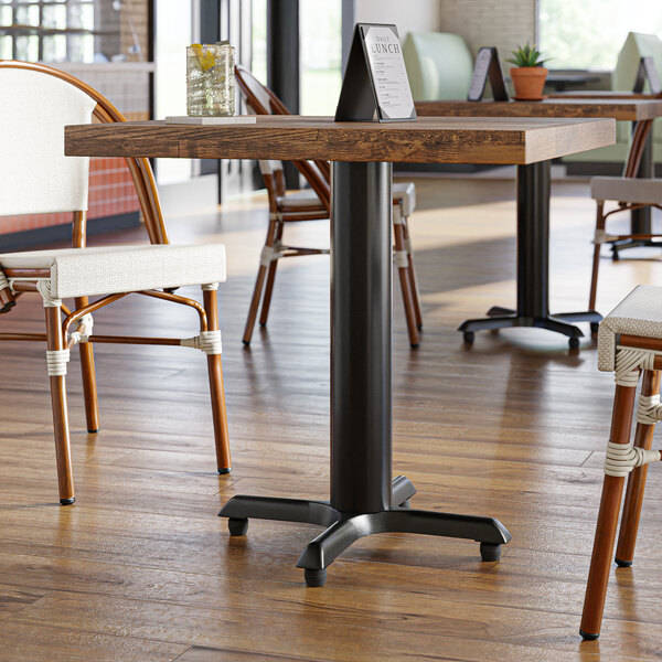 A Lancaster Table & Seating black cast iron table base with FLAT Tech levelers on a restaurant table.