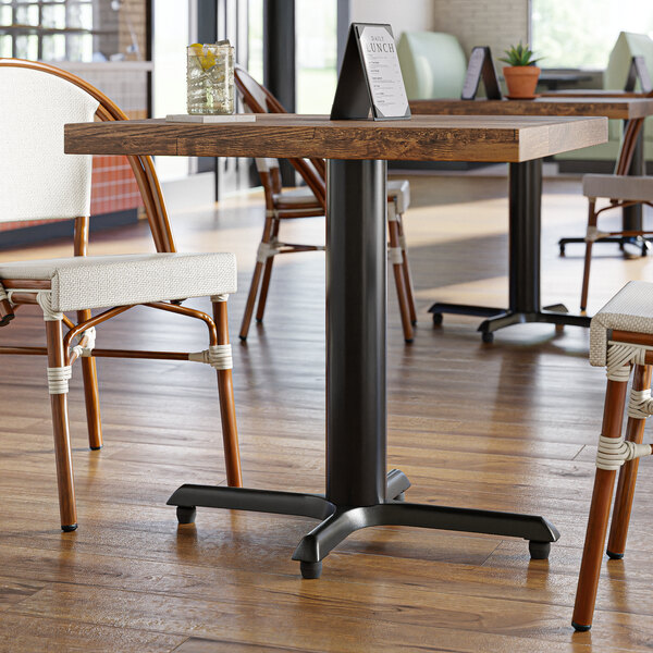 A Lancaster Table & Seating black standard height table base with FLAT Tech levelers on a table in a restaurant.