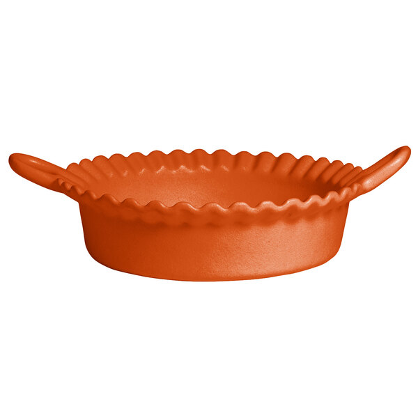 An orange round G.E.T. Enterprises Mexican cazuela with a wavy edge.