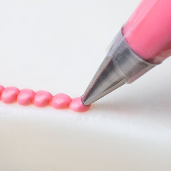 A close-up of a pink liquid being piped with an Ateco oval tip.