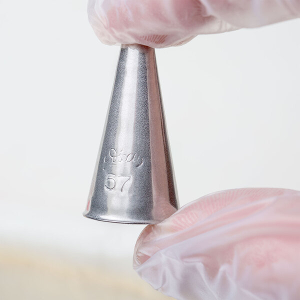 A hand holding a metal Ateco oval piping tip.