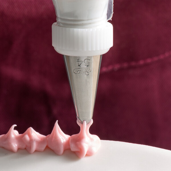 A cake being decorated with an Ateco Cross-Top piping tip in a pastry bag.