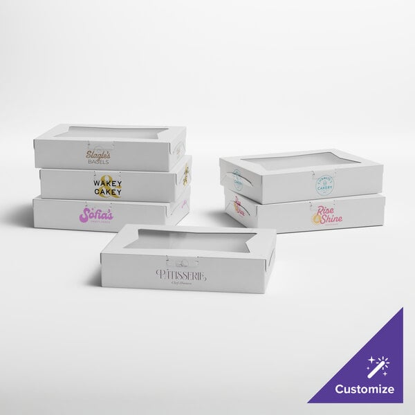 A set of white customizable window cake or bakery boxes, each with a clear top panel and various printed logos, displayed in a group.