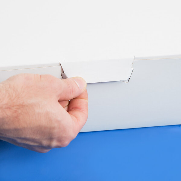 A hand opening a white 19" x 14" x 4 1/2" bakery box.