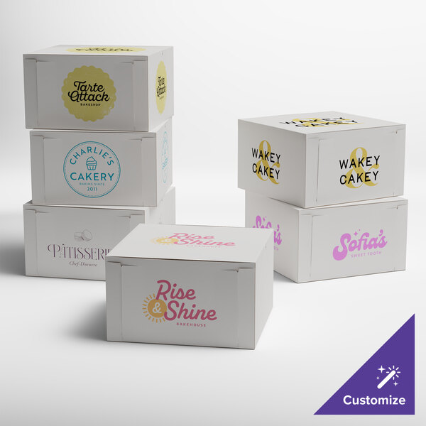 A stack of white customizable cake boxes with different designs on them.