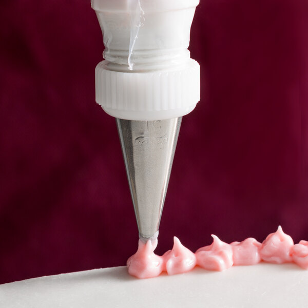 A cake being piped with pink frosting using an Ateco Cross-Top piping tip.