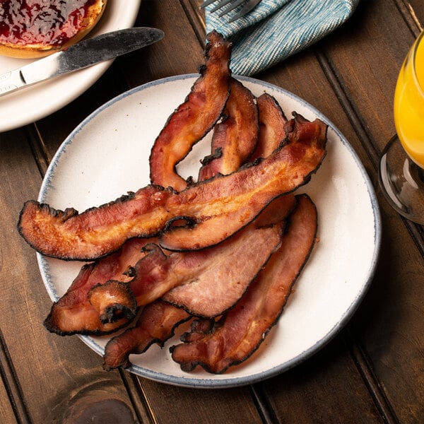 A plate of Kunzler Black Forest bacon with a glass of orange juice.