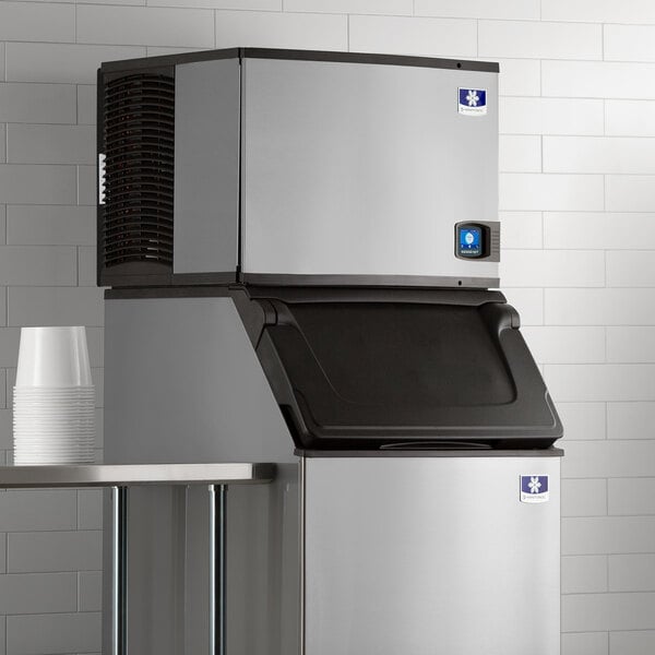 A large stainless steel Manitowoc air cooled ice maker on a counter.