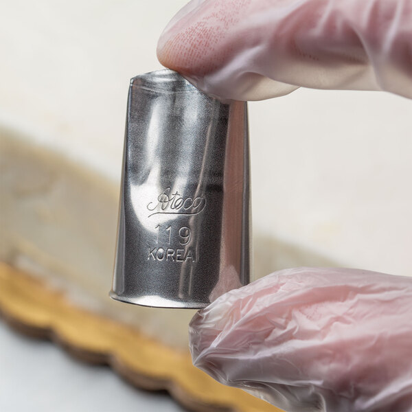 A person holding a silver Ateco rose piping tip.